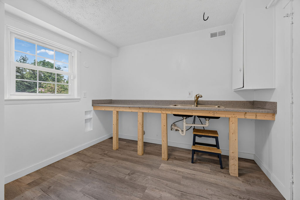 Lower-level utility room with a roughed-in kitchen sink on an unfinished counter, awaiting cabinetry