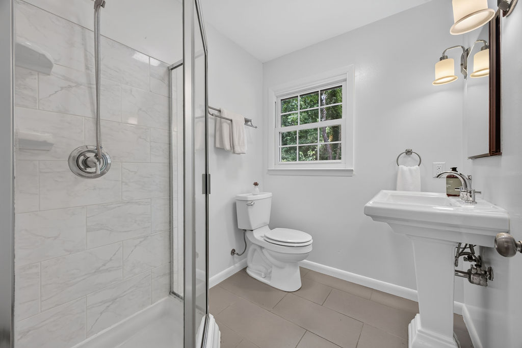 Bathroom with glass walk-in shower, marble-look tile and pedestal sink