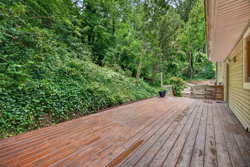 Expansive wood deck running the length of the house, overlooking a green wooded hillside
