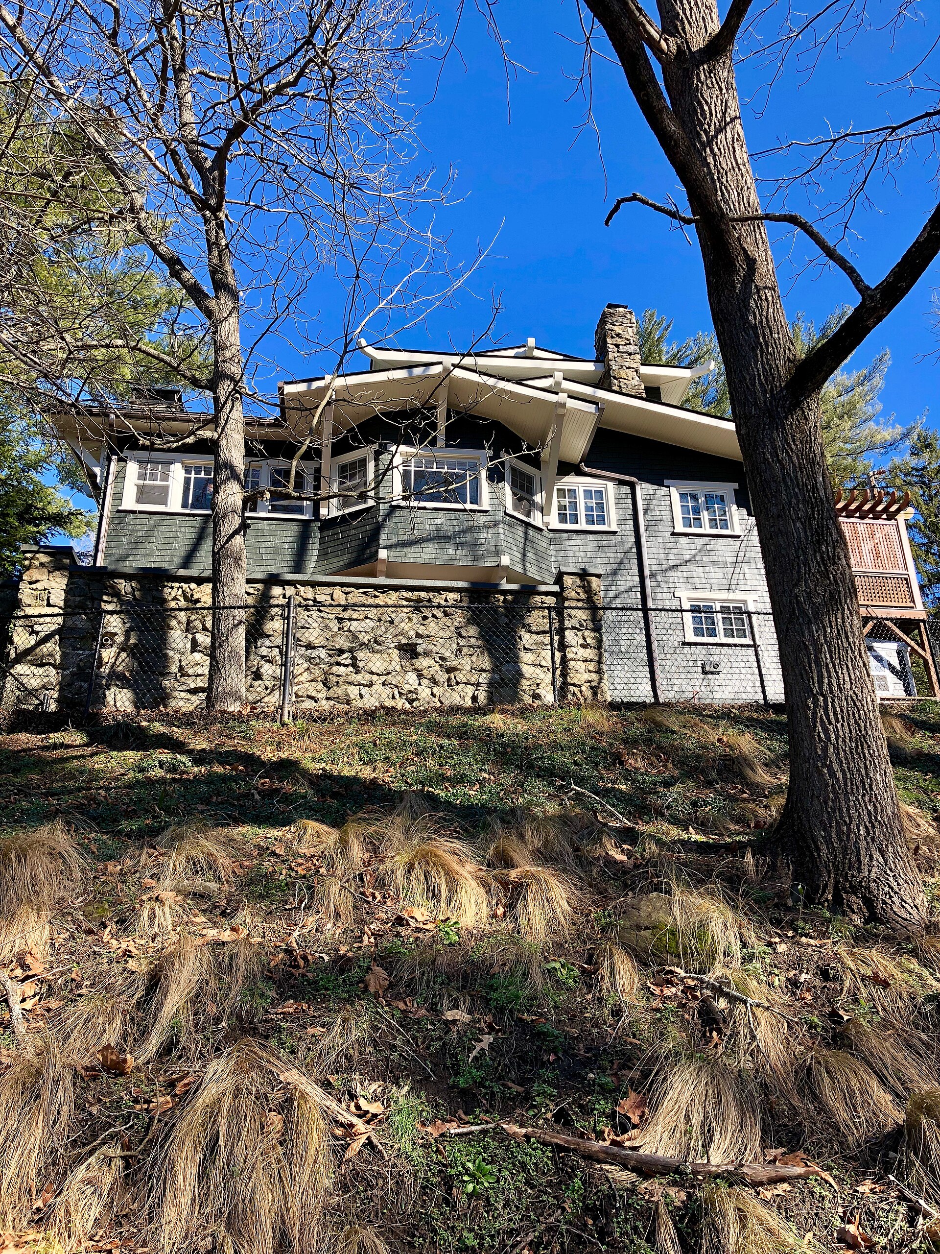A shingled Craftsman house on a stone base set into the hillside on Bowling Park Road in Kenilworth