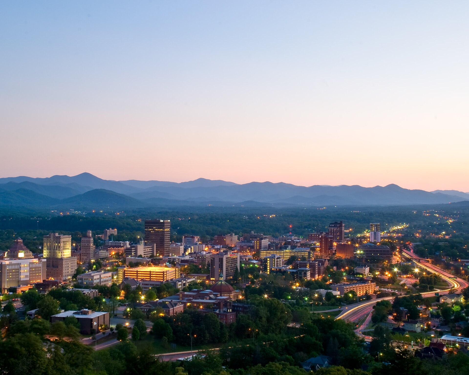 Asheville at dusk with the Blue Ridge Mountains layered on the horizon